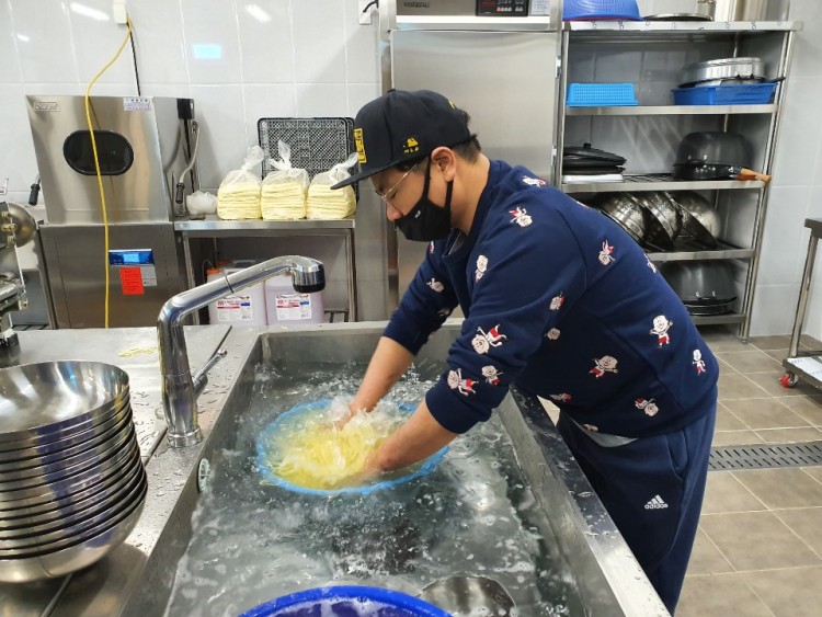 봉사자가 씽크대에서 면을 씻고 있는 모습